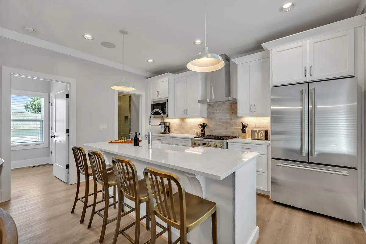 A welcoming kitchen featuring a spacious island with bar stools, sleek stainless steel appliances, and elegant cabinetry. The setup is open, ideal for group cooking, with plenty of workspace and modern amenities evident throughout.