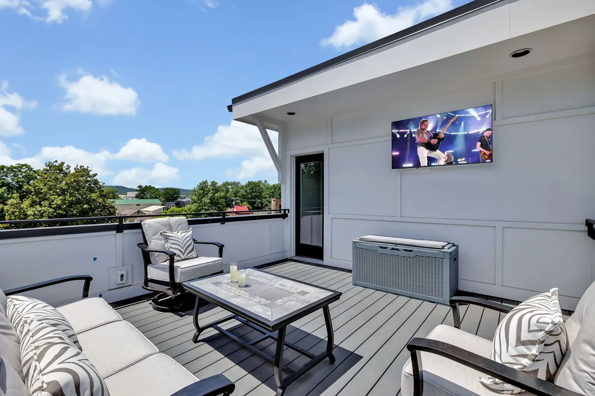 A spacious outdoor seating area featuring a television, decorative table, and comfortable chairs, set against a backdrop that encourages group gatherings and entertainment. The setup is perfect for hosting social events or relaxing after a day of exploring the city.