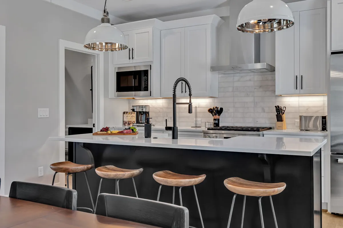 A contemporary kitchen with a large island, sleek stools, and high-end appliances arranged for comfortable meal prep and entertaining. The ambiance is both modern and welcoming, inviting guests to participate in culinary experiences.