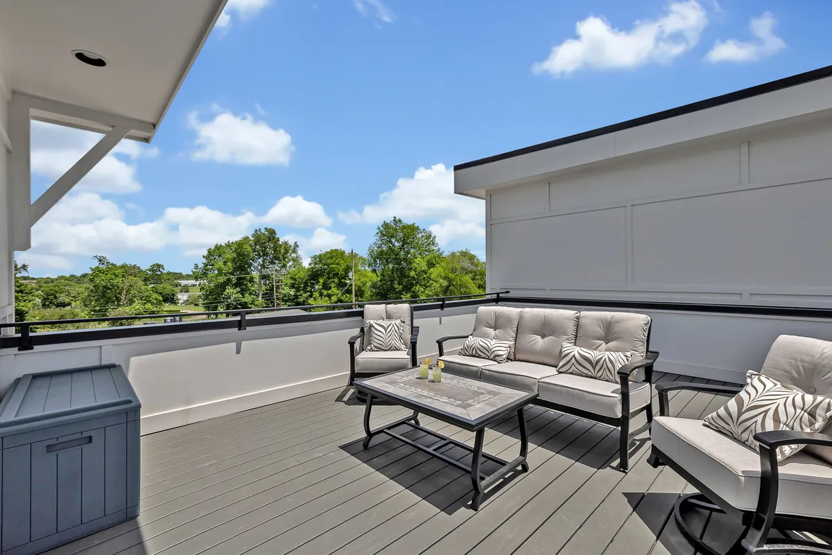 A stylish rooftop patio with comfortable outdoor seating and a coffee table, set against a scenic landscape view. The space exudes relaxation and exclusivity, perfect for evening gatherings or unwinding after a night out.
